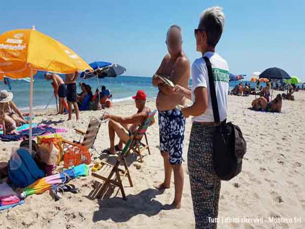 donna che sensibilizza persone al mare sulla differenziata