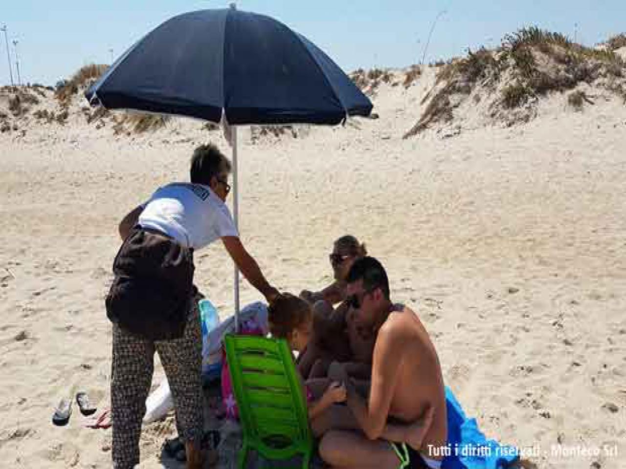 donna che sensibilizza persone al mare sulla differenziata