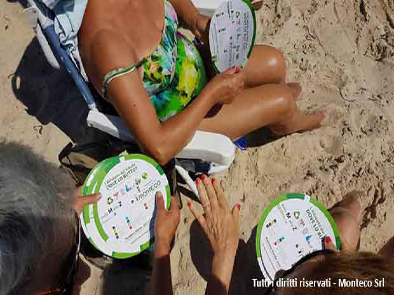 donna che sensibilizza persone al mare sulla differenziata, consegnando ruota dei rifiuti