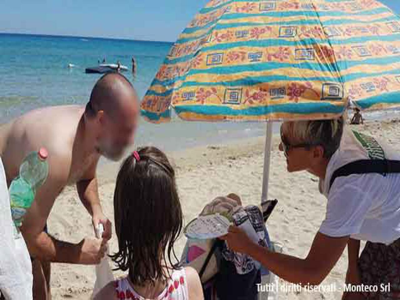 donna che sensibilizza persone al mare sulla differenziata