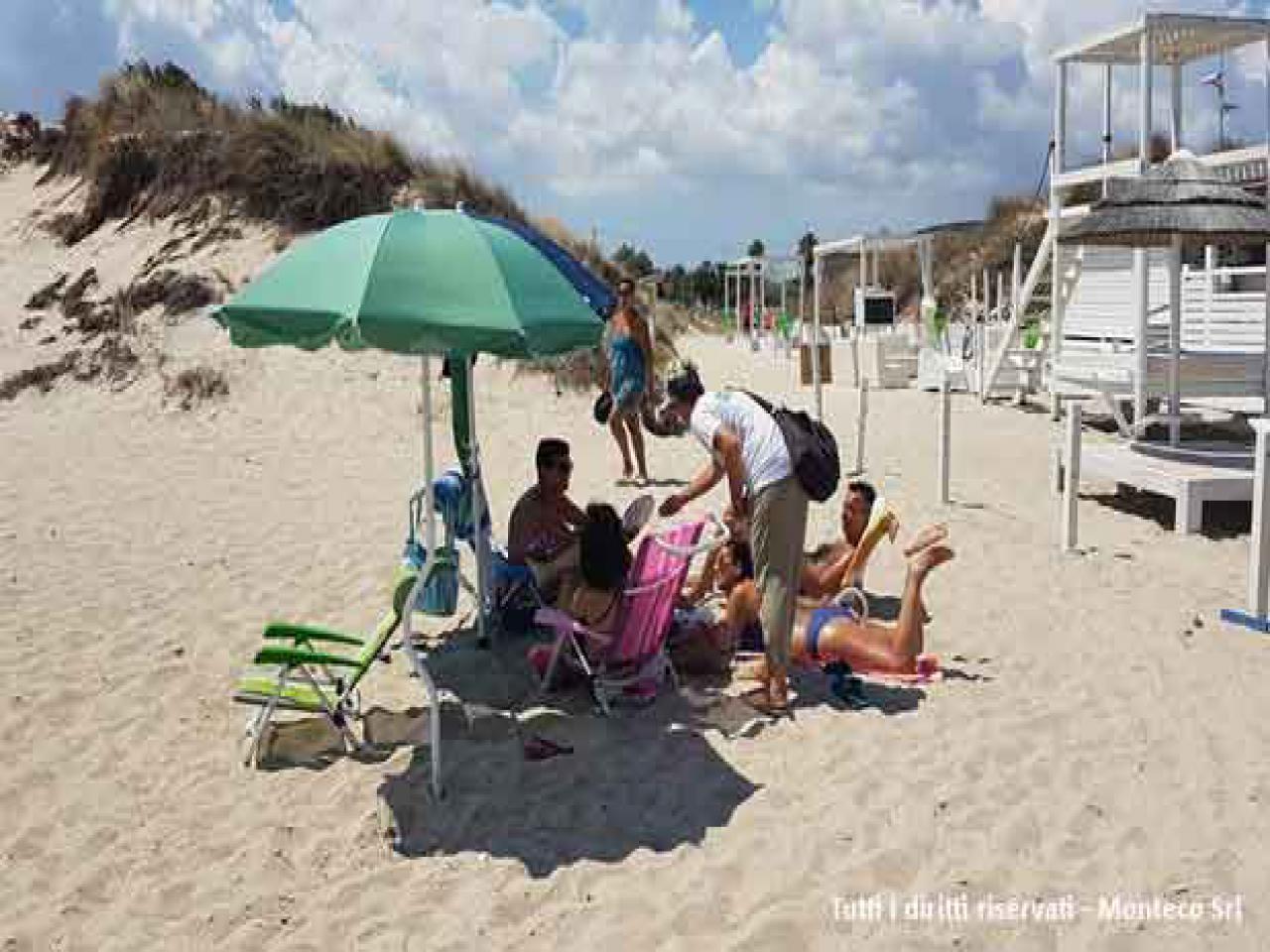 donna che sensibilizza persone al mare sulla differenziata