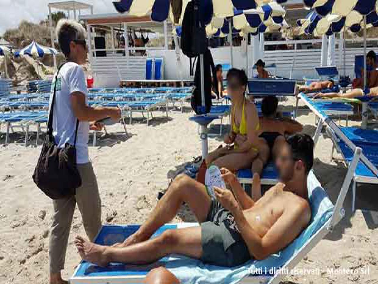 donna che sensibilizza persone al mare sulla differenziata